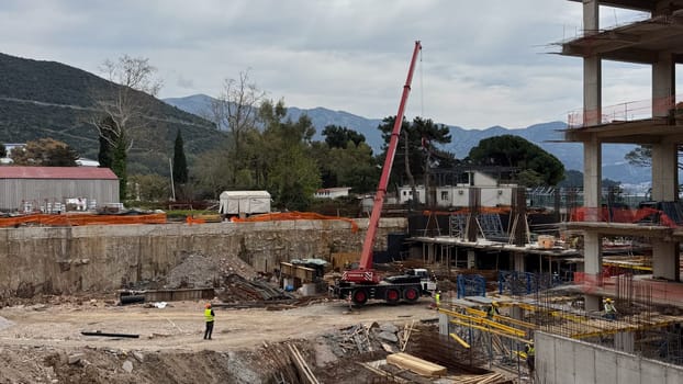 Budva, Montenegro - April 18, 2025: Construction site depicting workers and machinery in a mountainous area, highlighting the development process and growth of industry