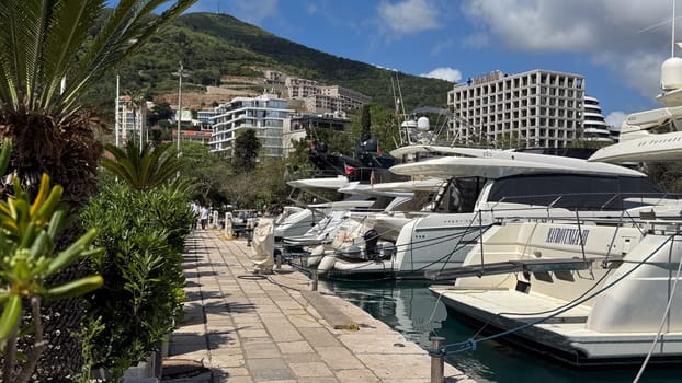 Budva, Montenegro - April 18, 2025: Luxury yachts moored in a marina surrounded by picturesque mountains and lush greenery