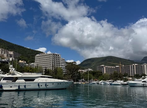 Budva, Montenegro - April 18, 2025: A marina with luxury yachts and modern buildings set against a picturesque coastal landscape