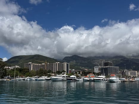 Budva, Montenegro - April 18, 2025: A view of the promenade with yachts and modern buildings against a backdrop of majestic mountains, highlighting the beauty of coastal life