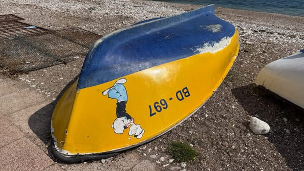 Budva, Montenegro - April 18, 2025: A colorful boat featuring a cartoon character stands on the seashore, showcasing playful maritime art and creativity in the coastal area