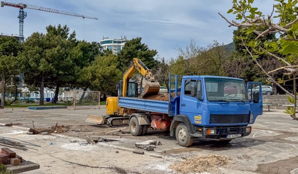 Budva, Montenegro - April 18, 2025: Construction site showcasing a blue truck alongside an excavator, emphasizing urban development and progress