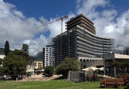 Budva, Montenegro - April 18, 2025: Construction of the large Hotel Falcons next to the waterfront, construction crane and ongoing works.