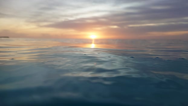 Tranquil scene featuring a vibrant sunset casting colorful reflections on the calm ocean surface, evoking a peaceful and serene atmosphere perfect for relaxation and contemplation