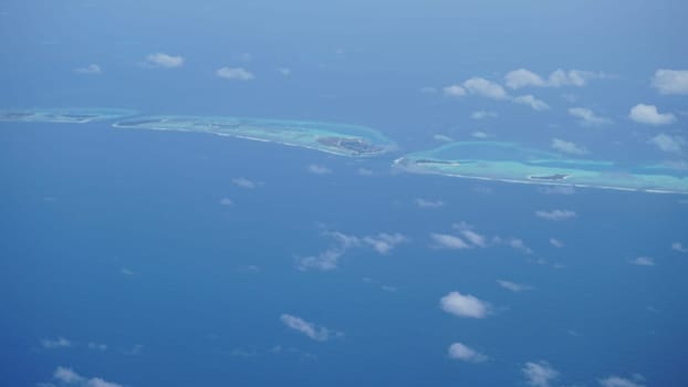 Breathtaking aerial view revealing the maldives' stunning turquoise waters lapping against idyllic islands adorned with lush vegetation under a serene sky