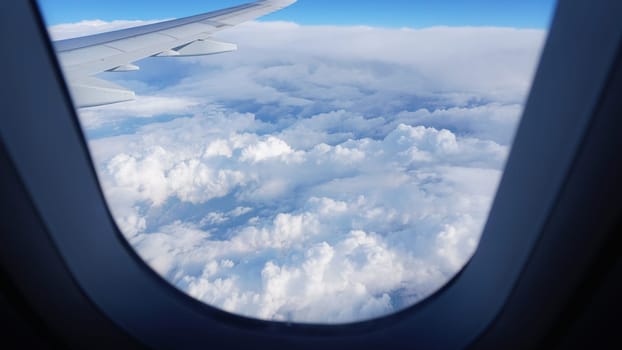 View from an airplane window, showing the wing and a breathtaking expanse of cumulus clouds below, creating a mesmerizing scene of aerial tranquility