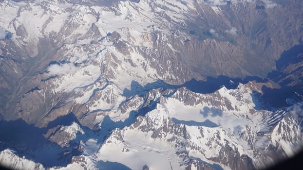 Breathtaking aerial perspective of majestic snow-capped mountain peaks casting long shadows over the valleys below, creating a dramatic landscape