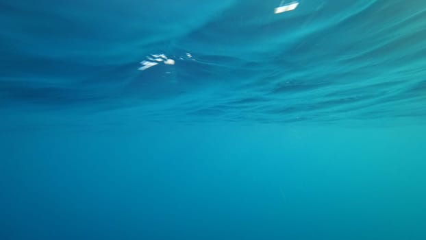 Sunlight filtering through the rippling surface of a tranquil turquoise ocean creates a mesmerizing underwater scene, perfect for evoking a sense of serenity and wonder