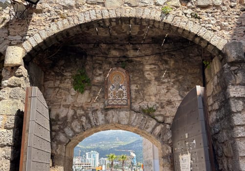 Budva, Montenegro - April 18, 2025: The historic stone arch of the old town, decorated with religious iconography, is located in the cultural heritage site of the coastal city