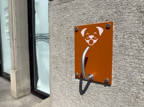 Dog leash hook installed outdoors for pet owners to secure their dogs safely. Happy dog face icon adds friendly touch, promoting responsible pet ownership in modern urban areas