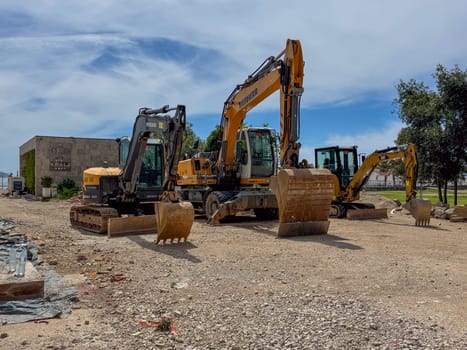 Budva, Montenegro - April 18, 2025: Construction equipment from Volvo, Liebherr and Caterpillar stands on the site near the coastal restaurant KRALJ.