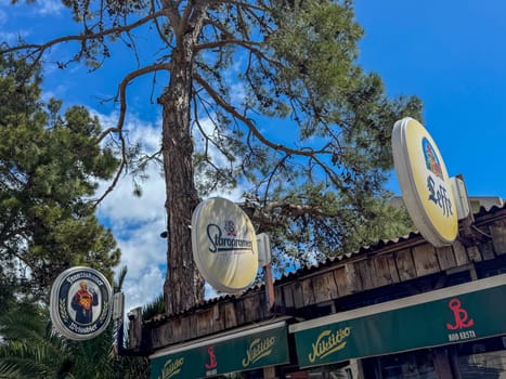 Budva, Montenegro - April 18, 2025: Staropramen, Niksicko, Franziskaner Weissbier brand name on the canopy of the KOD KRSTA bar under the tree