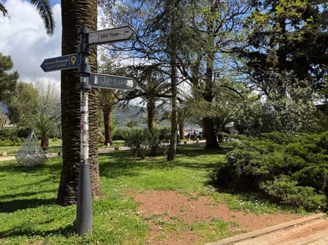Budva, Montenegro - April 18, 2025: Directional signs in a tranquil park-like environment inviting visitors to explore local attractions and nature