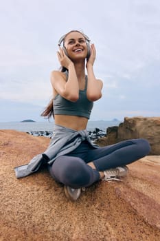 Cheerful female model in sportswear, listening to music outdoors, embodies joy and relaxation while surrounded by nature, highlighting a balanced lifestyle