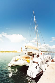 Catamaran moored at marina on sunny day with clear blue sky and calm water
