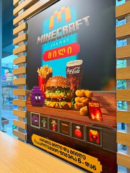 Tbilisi, Georgia, April 9, 2025: Promotional poster with pixel style graphic advertising Minecraft and McDonald's collaboration. Burger, fries, special sauce and Coca Cola in video game themed design
