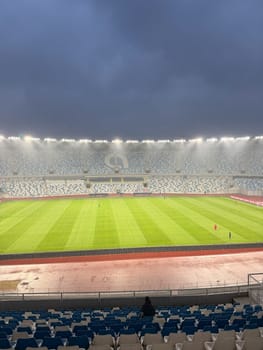 Tbilisi, Georgia, April 9, 2025: Wide view from the stands at Dinamo Tbilisi stadium, showcasing the empty arena and green football pitch under stadium lights