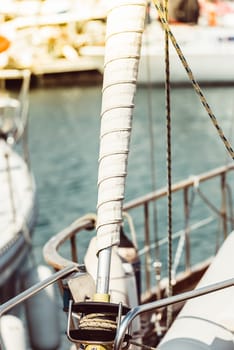 Sailboat mast with wrapped sail detail in marina setting, ideal for nautical background