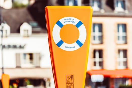 Orange life buoy station with signage on urban street, background