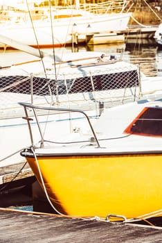 Yellow sailboat in sunny marina setting with several other boats, perfect for summer background