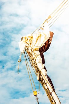 Sailboat mast against cloudy sky, with rigging details, vertical format, background