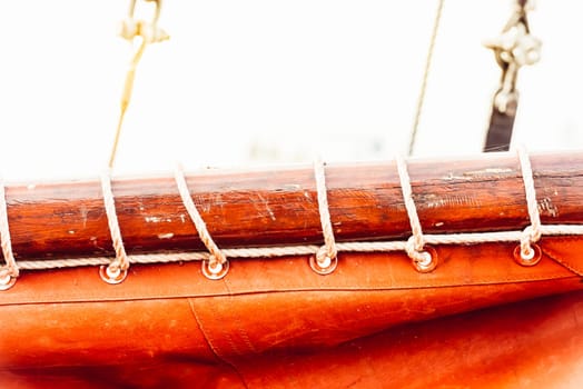 Sailboat mast and ropes with vibrant orange sail creating nautical background