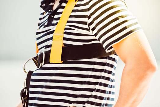 Man wearing safety harness, black and white striped shirt, safety concept