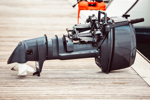 Boat motor on wooden dock near water, suitable for marine backgrounds