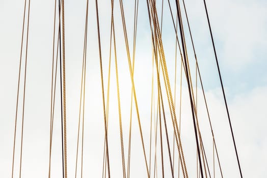 Rope cables against cloudy sky create industrial abstract pattern, background