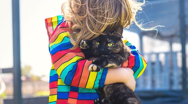 Child hugging a cat on the street. Selective focus. kid.