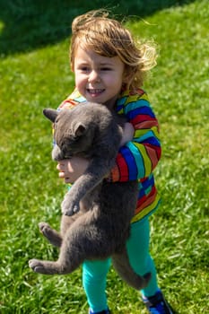 Child hugging a cat on the street. Selective focus. kid.