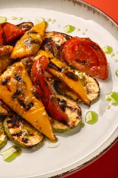 Grilled vegetables with pesto sauce on a plate: zucchini, bell peppers, tomatoes, and mushrooms