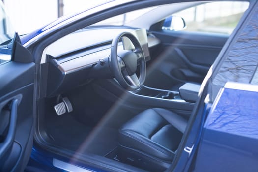 Steering wheel of a electric vehicle, interior cockpit, electric buttons, digital speedometer, front seats, textile, windows, console, gear shift. Car dashboard with a digital touchscreen.