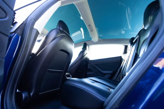 Panoramic glass sun roof in the modern electric car. Clean sunroof and view at the sky from the inside or car interior. The view from the empty car with rear seats.