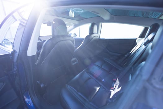 Hatch in car roof. Panoramic glass sun roof in the car. Clean glass and view from inside to the sky. Double sunroof hatch with tinted glass. Rear leather passenger seats in modern lux electric car.