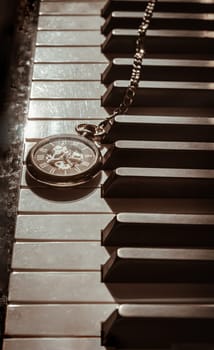 London, UK - Apr 19, 2025 - Perspective of Retro pocket watch or Antique pocket watch on Piano keys background in Vintage tone. "keys and time" use it as your Wallpaper, Poster and Copy space, Selective focus.