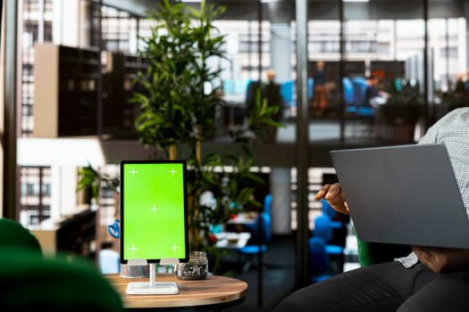 Green screen tablet and laptop used by staff member preparing for business meeting. Mockup device next to office clerk using notebook in startup to do research analysis, reading documents online