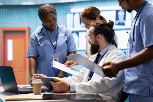Doctors team review human anatomy scans to develop treatment plans, discussing potential diagnosis. Licensed healthcare specialists working together to provide insurance medical services.