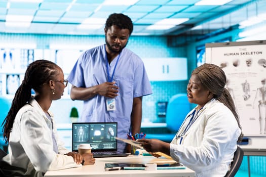 Black girl interacting with a general practitioner in a medical cabinet, discuss MRI and x ray analysis for personalized care. Medic offers wellness and guidance during scan interpretation.