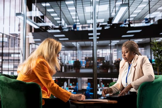 Female executives review legal paperwork and finalizing an important deal, singing banking documents and highlighting progression. Productivity in a male dominated business industry.