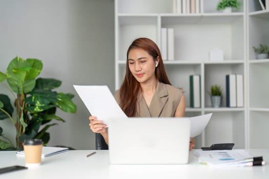 While on a video call, a woman reviews her documents to ensure accuracy and clarity, highlighting the importance of effective communication.