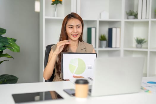 Focused on her analysis, a business professional reviews data while seamlessly conducting a remote meeting, demonstrating multitasking in a modern workspace.