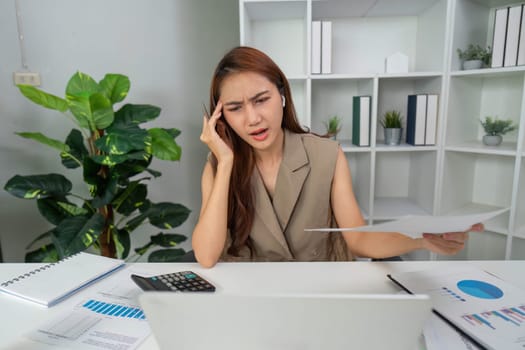 Amidst her workspace, a woman shows visible signs of strain while managing difficult financial information, emphasizing the challenges faced in the modern work environment.