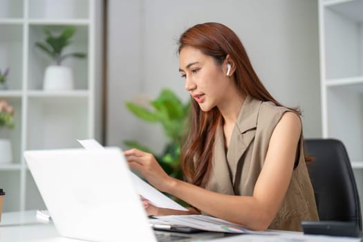 During a virtual meeting, a woman pays keen attention to her paperwork, emphasizing the importance of detail in effective communication.
