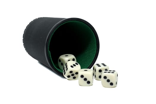 Shot of a black dice cup that has been tipped on its side, spilling out five white dice on a white surface.