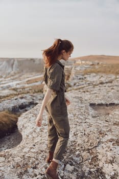 Adventure in the wilderness a woman in a green jumpsuit ascending a rocky outcropping on her journey