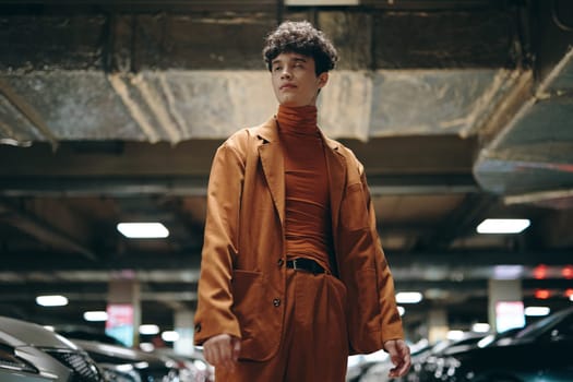 A fashionable individual wearing a brown suit and turtleneck in an urban parking garage setting, highlighting contemporary style