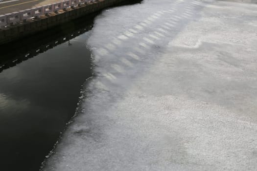 A fragment of the embankment, a river covered with snow and ice, a shadow on the snow.
