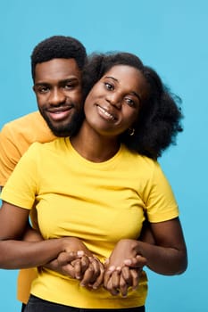 A joyful young African couple wearing matching yellow t shirts stands together against a bright blue background, symbolizing love and togetherness Their smiles convey happiness and connection