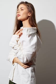 A profile shot of a woman wearing a white shirt, exhibiting grace and style, with soft lighting and a simple light background, ideal for fashion and lifestyle projects